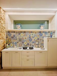 a kitchen with a tile wall with two faces on it at Riviera del Mare House in Siracusa +33 photos