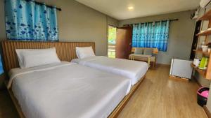 a bedroom with two beds with blue curtains at ID Garden Home in Ban Cham Kha