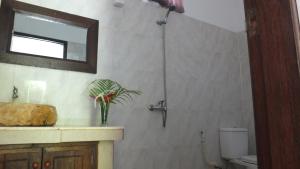 a bathroom with a sink and a shower with a mirror at Ricel Homestay in Gili Trawangan
