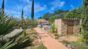 a garden with a stone building and a pathway at Aux trois Cyprès Salernes en Provence in Salernes