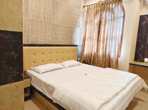 a bedroom with a bed with white sheets and a window at Sri Lakshmi inn in Coimbatore