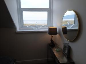 a room with a mirror and a lamp and a window at Seashell Apartment in Barmouth