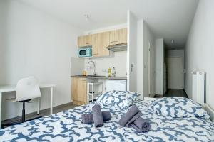 a bedroom with a blue and white bed and a kitchen at Le studio du Pont Guilhemery in Toulouse