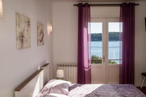 a bedroom with a bed and a window with purple curtains at B&B Sabina Rooms & Apartments in Rab