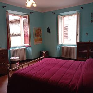 a bedroom with a large bed and two windows at Casa 28 Luglio - Appartamento in Mercatello sul Metauro