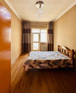 a bedroom with a bed and a window and a chandelier at City Center in Ulaanbaatar +1 photo