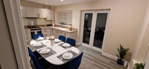 a kitchen with a white table and blue chairs at Spacious Colchester Home with Off-Street Parking for 4 cars in Colchester