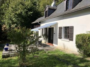 a white house with a blue awning and a yard at Mountain View in Arcizans-Avant