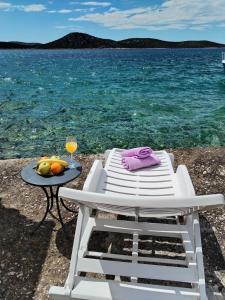 a white chair and a table with a glass of juice at Ema in Prvić Šepurine