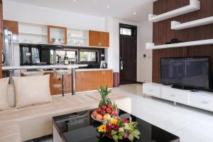 a living room with a television and a bowl of fruit on a table at Khách sạn Le Domaine De Cocodo in Hue