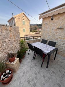 a patio with a table and chairs and a stone wall at Lavanda Apartment in Stari Grad