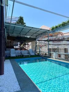 a swimming pool with white chairs and an umbrella at SnS Muine Homestay in Mui Ne
