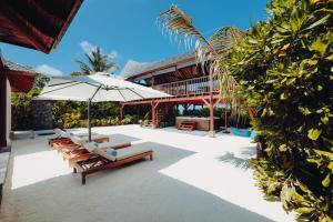 马纳杜岛Kuredhivaru Resort and Spa - Maldives的户外庭院设有躺椅和遮阳伞。