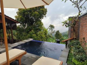 a swimming pool in a backyard with an umbrella at Ganayu Bali Villa in Munduk