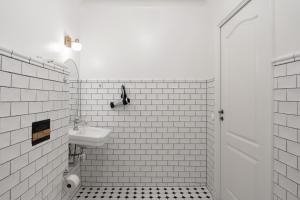 a white tiled bathroom with a sink and a toilet at Hotell Skeppsbron in Stockholm
