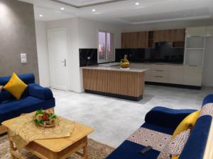 a living room with blue couches and a kitchen at appartement l 'Oasis in Shanīnī
