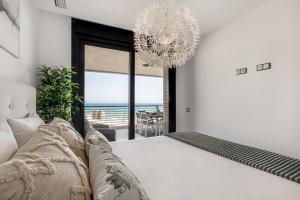 a bedroom with a bed and a chandelier at INFINITY View Amazing Beachfront Apartment in Arenales del Sol +45 photos