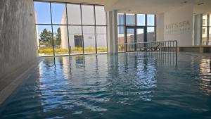 a swimming pool in front of a building with windows at Sea Baltic Apartament Gąski - basen in Gąski