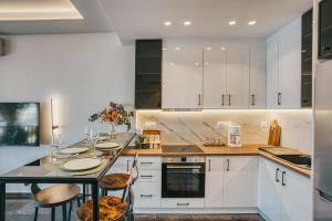 a kitchen with white cabinets and a table with chairs at NOA-Luxury Stay with a view in Chios