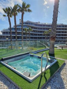 a hot tub with palm trees and a building at INFINITY View Amazing Beachfront Apartment in Arenales del Sol