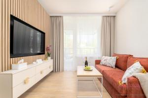 a living room with a red couch and a flat screen tv at Your Holidays Bel Mare Aqua in Międzyzdroje