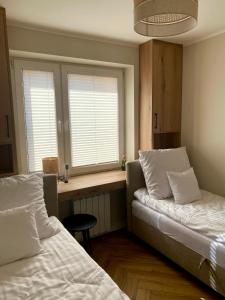 a bedroom with two beds and a desk and two windows at uDany w Goniądzu in Goniadz