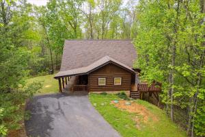 a log cabin in the woods with a driveway at Dog Friendly, Hot Tub, Game Room, Ev Charger in Gatlinburg