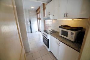a kitchen with white cabinets and a microwave at Holiday Home Suites in Beirut