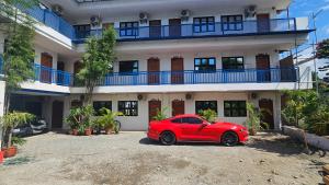 a red car parked in front of a building at San Juan Hostel in Sampong