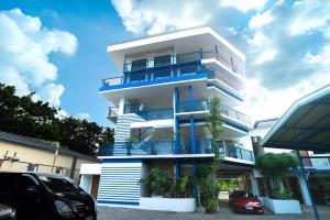 a tall white building with blue balconies and a car at San Juan Hostel in Sampong