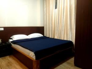 a bedroom with a bed with blue sheets and white pillows at Shillong Rains Inn in Shillong