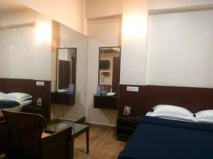 a room with a bed and a table and a mirror at Shillong Rains Inn in Shillong
