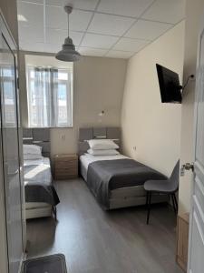 a bedroom with two beds and a tv and a chair at Hotel Ticha in Shumen