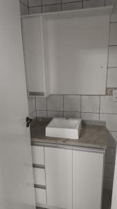 eine weiße Küche mit einer Spüle auf einer Theke in der Unterkunft Apartamento na melhor localização da meia praia em itapema com garagem para camioneta suv in Itapema + 11 Fotos