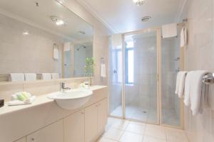a white bathroom with a sink and a shower at Melbourne Metropole Central Official in Melbourne