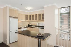 a kitchen with wooden cabinets and a black counter top at Melbourne Metropole Central Official in Melbourne