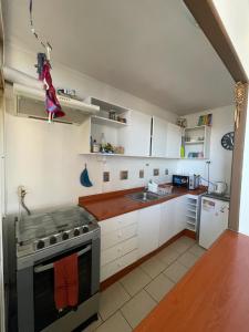 a kitchen with white cabinets and a stove top oven at Departamento Amoblado y equipado. in Talca