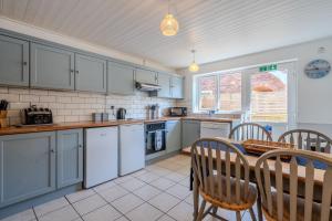 a kitchen with white appliances and a table and chairs at Cobbles End by Winterton Cottages in Winterton-on-Sea
