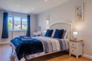 a bedroom with a large bed with blue pillows at Cobbles End by Winterton Cottages in Winterton-on-Sea