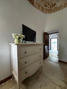 a dresser with a tv and flowers on top of it at I Trulli di Mimì in Monopoli