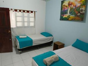 Una pequeña habitación con dos camas y una ventana. en Alojamiento LETICIA, en Leticia