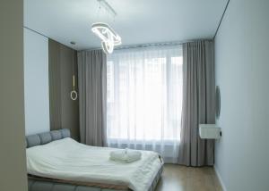 a bedroom with a bed and a large window at Alfarabi27-56 in Almaty