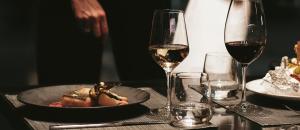 un tavolo con un piatto di cibo e due bicchieri di vino di The Blackpine Hotel - Small Luxury Hotels a Escaldes-Engordany