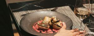 una persona che tiene un piatto di cibo in un wok di The Blackpine Hotel - Small Luxury Hotels a Escaldes-Engordany