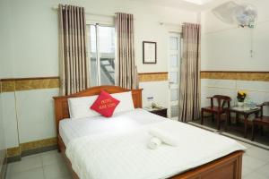 Schlafzimmer mit einem Bett mit weißer Bettwäsche und roten Kissen in der Unterkunft khách sạn Kim Long in Ho-Chi-Minh-Stadt