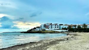 a beach with a building on a hill next to the water at Roda playa in Roda de Bará