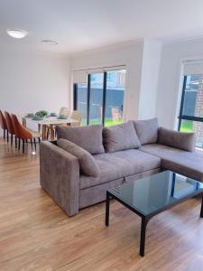 a living room with a couch and a table at Colebee 4 Bedroom House Walk to Park and Shops in Schofields