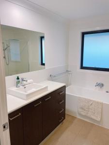 a bathroom with a sink and a tub and a sink and a mirror at Colebee 4 Bedroom House Walk to Park and Shops in Schofields