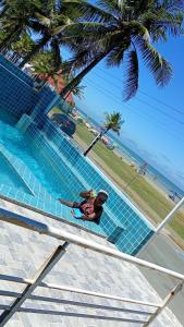 Un hombre tumbado en una piscina junto a una playa. en Pousada do Vaqueiro, en Peruíbe
