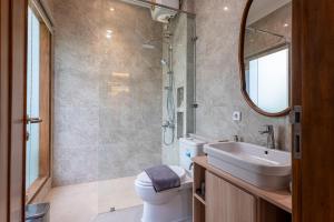a bathroom with a sink and a toilet and a mirror at Kalynda Boutique Villa in Kejayan